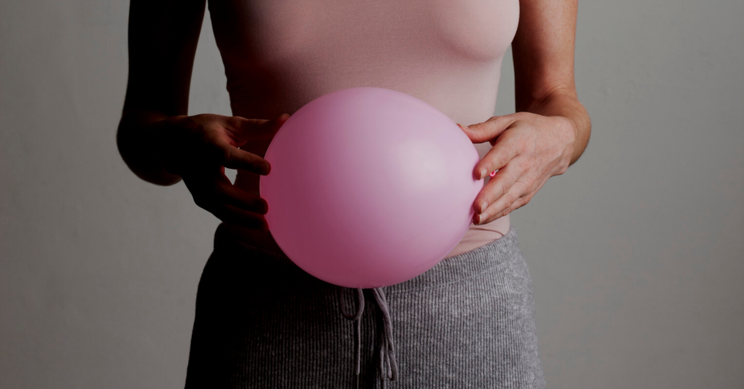 A person holding balloon in front of his stomach to show that he is having bloating in his stomach.