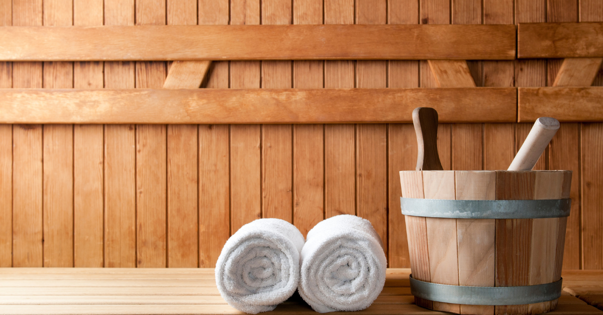 Two Towels & a wooden bucket placed in a sauna room.