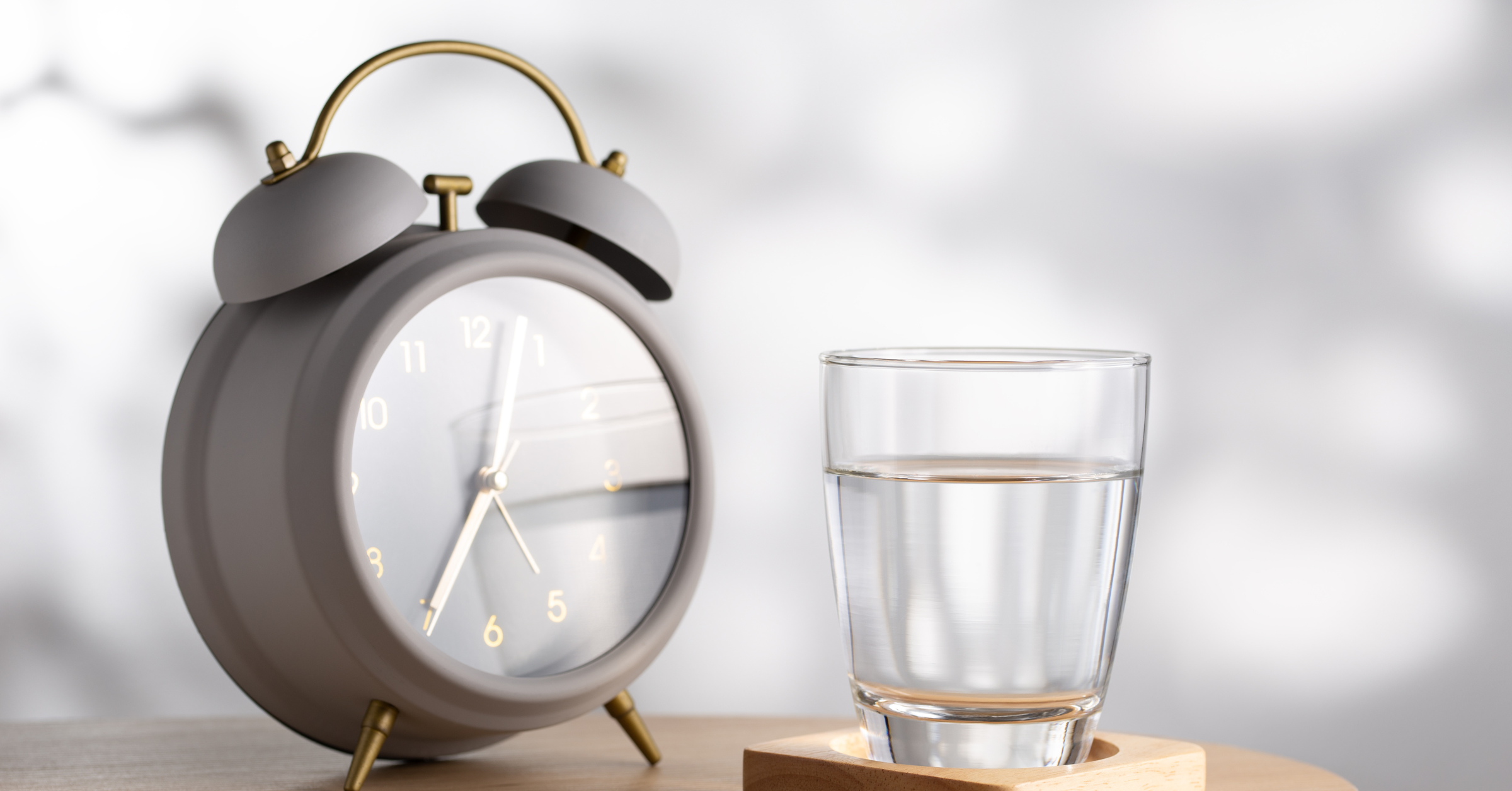 An alarm clock & a glass of water placed on the table
