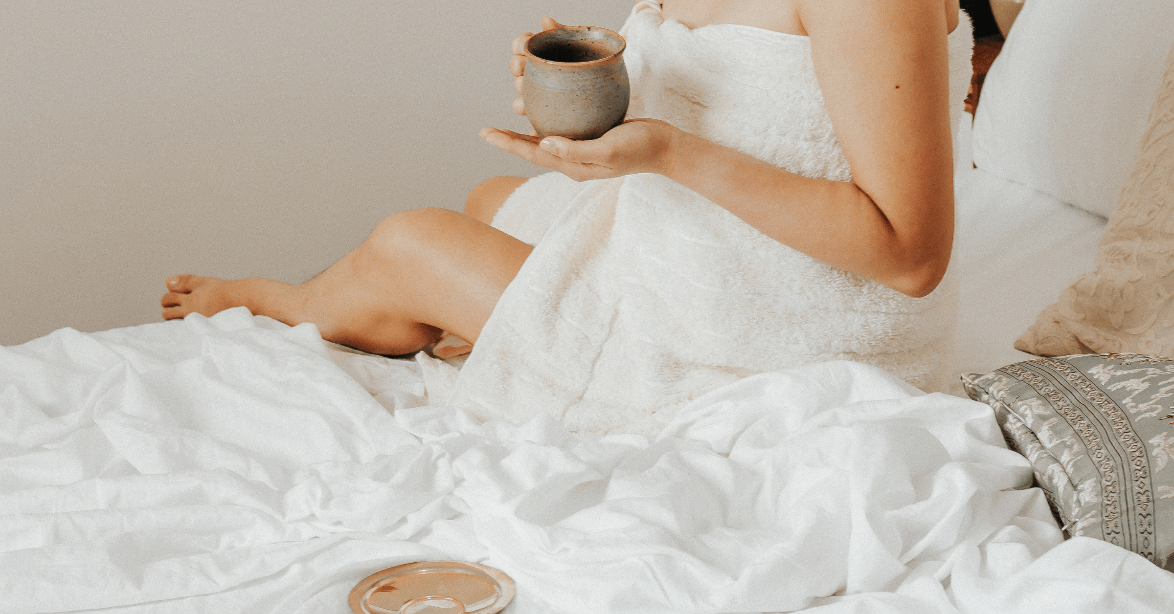 a woman holding coffee mug on the bed