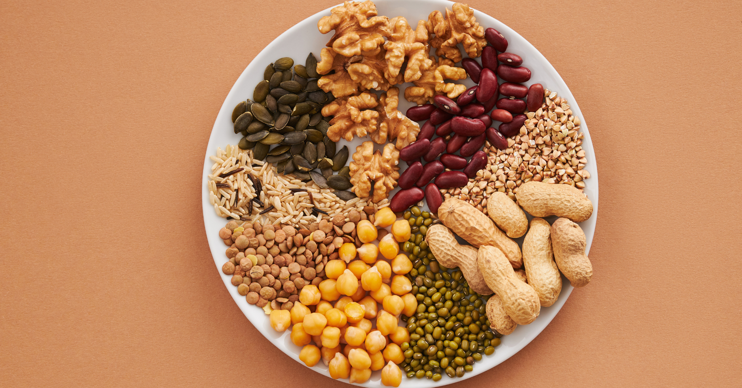Different types of nuts & dry-fruits are placed on a white plate.