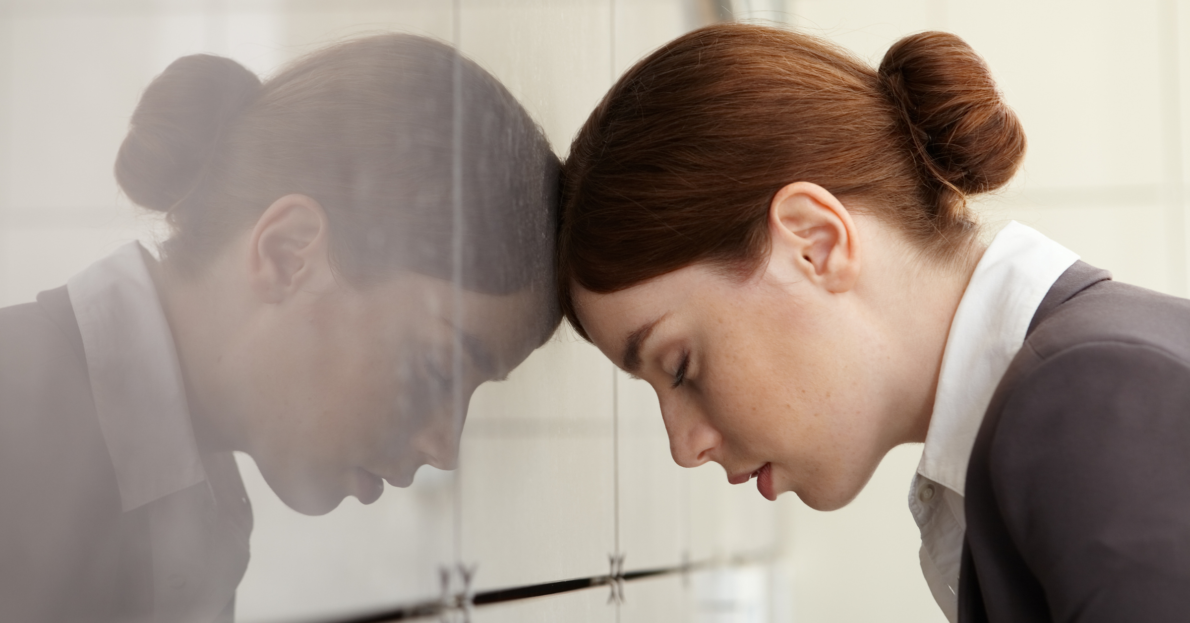 A woman placed her head to the mirrored wall, seems to be in pain